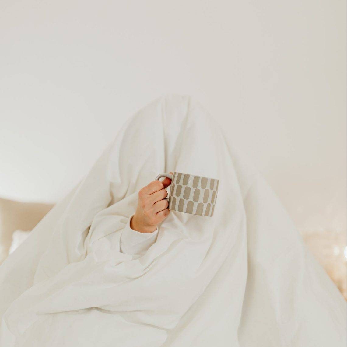 Photo by Karolina Grabowska: https://www.pexels.com/photo/person-hiding-under-a-white-blanket-holding-a-ceramic-mug-6660832/